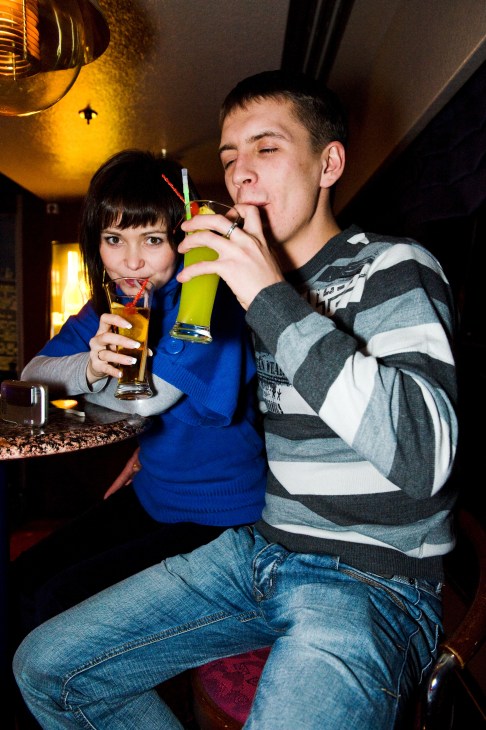 Two young passengers drinking cocktails with straws in a dimly lit bar on the M/S Gabriella ferry.