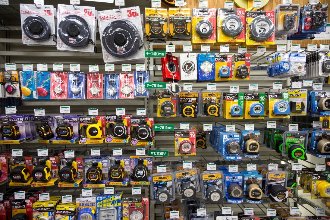 Shelves displaying a wide variety of tape measures in different sizes and colors at Tokyu Hands.