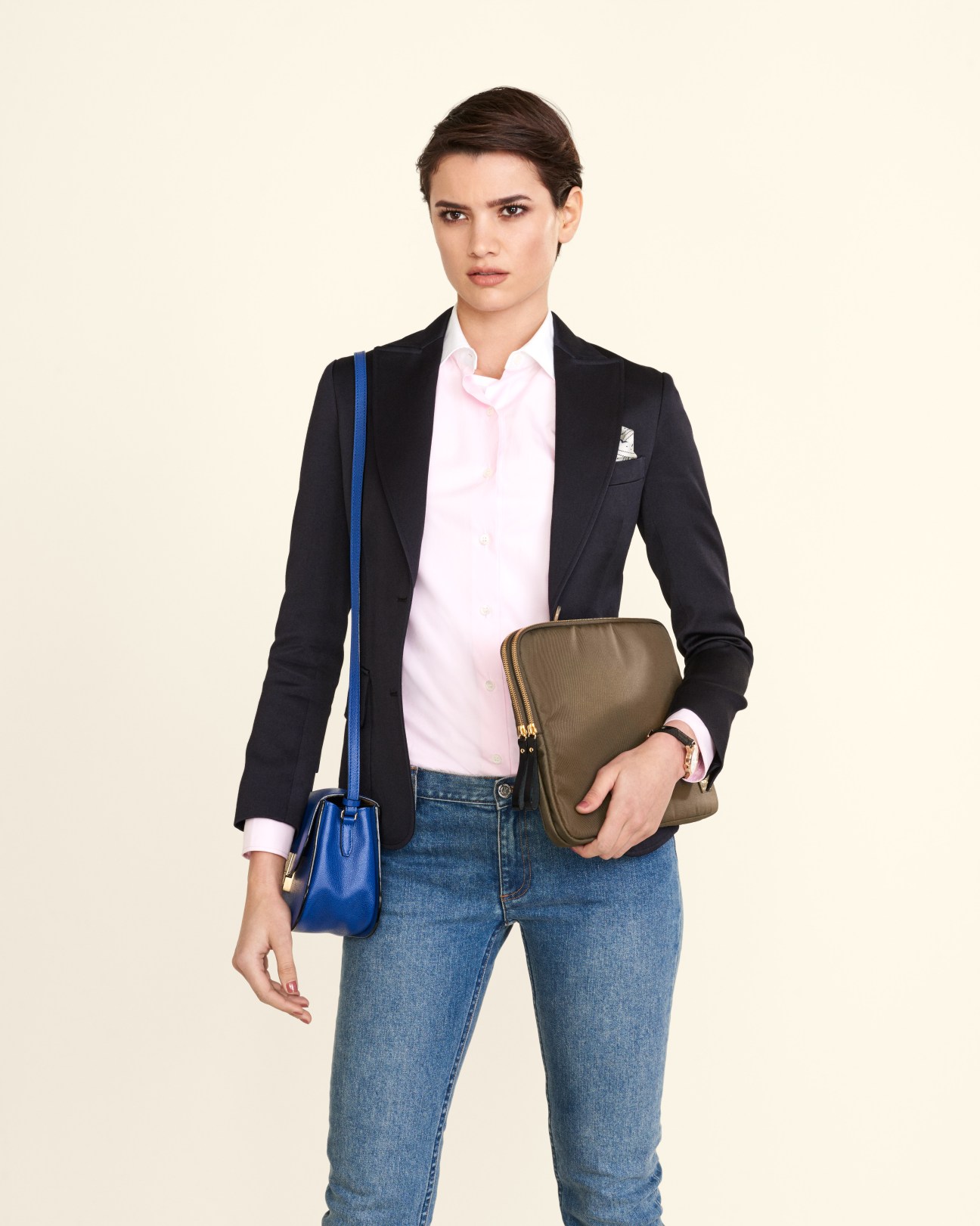 Model wearing black Madisonblue jacket, pink shirt, APC jeans, and holding Valextra bag and Porter portfolio case.