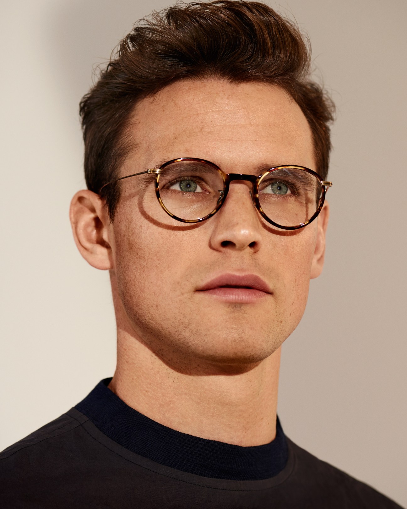 Man wearing tortoiseshell glasses and a short-sleeved pullover by Scye