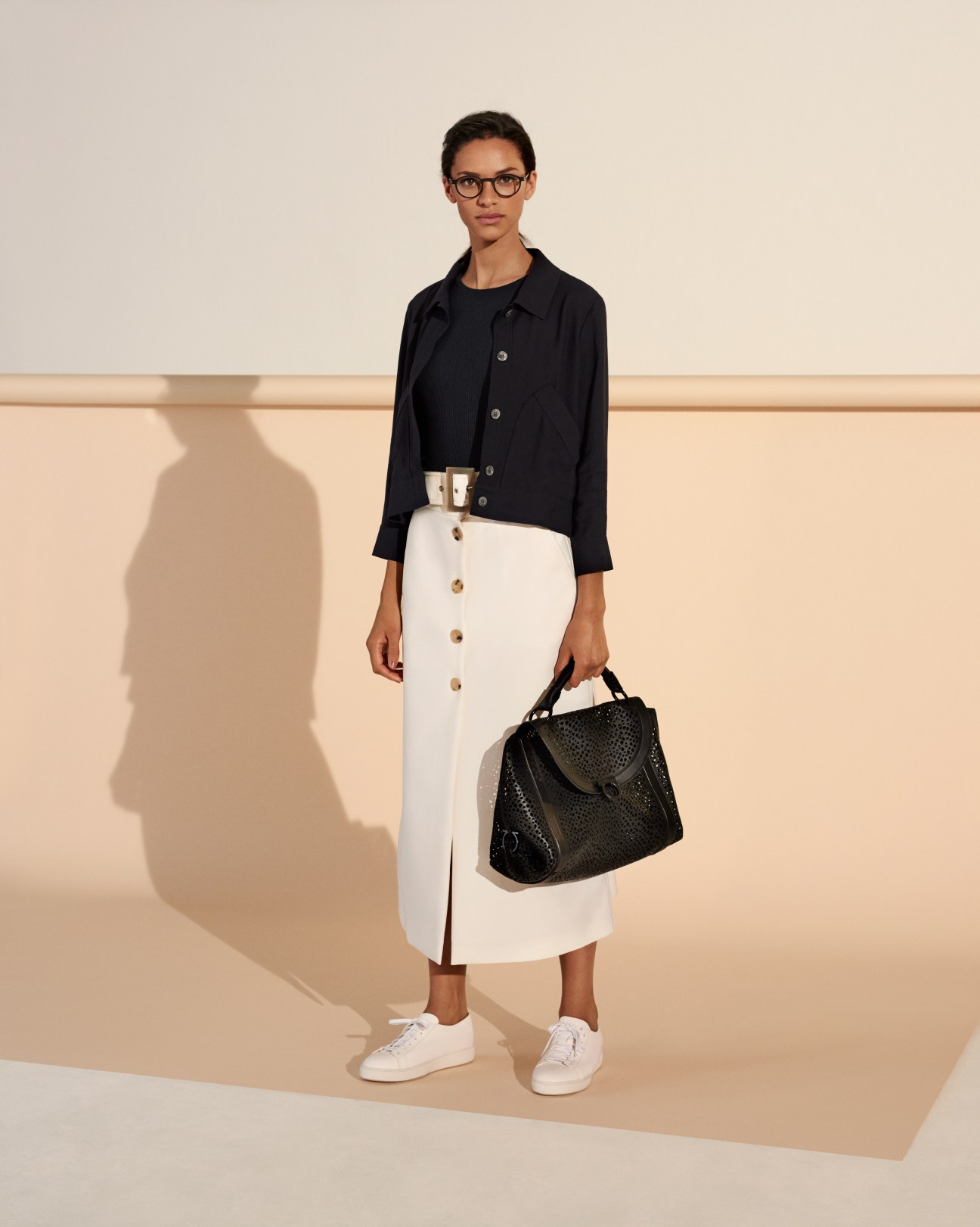 Model wearing Maison Kitsuné jacket, Norse Projects pullover, Bella Freud skirt, Santoni trainers, Lindberg glasses and Salvatore Ferragamo bag.