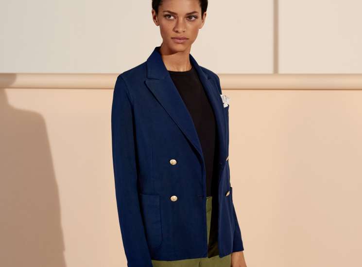 Model wearing navy blazer by Circolo 1901, black t-shirt by Sunspel, and olive shorts by Vince.