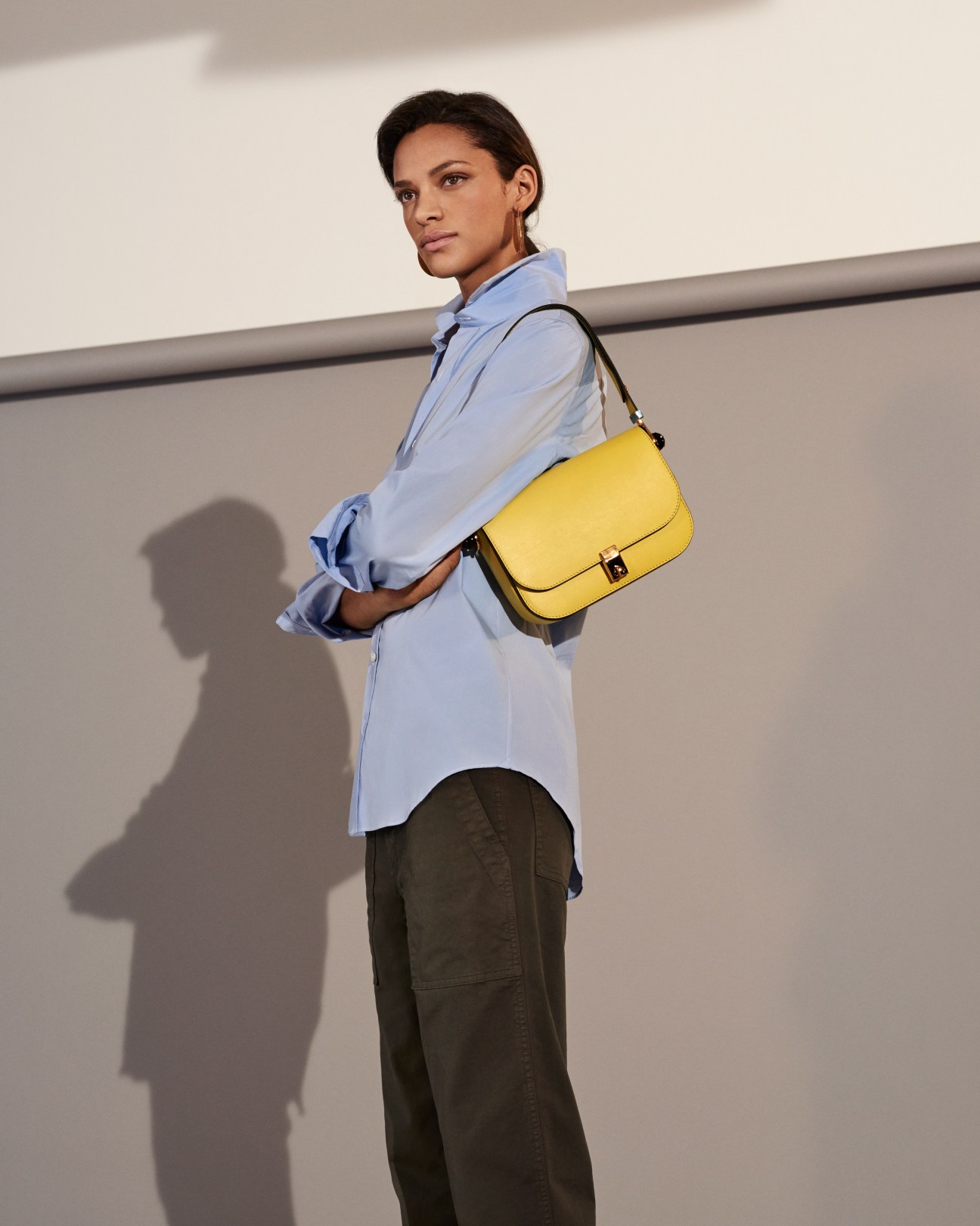 Woman wearing light blue shirt by Salvatore Piccolo, olive trousers by Barena, and yellow Valentino bag.