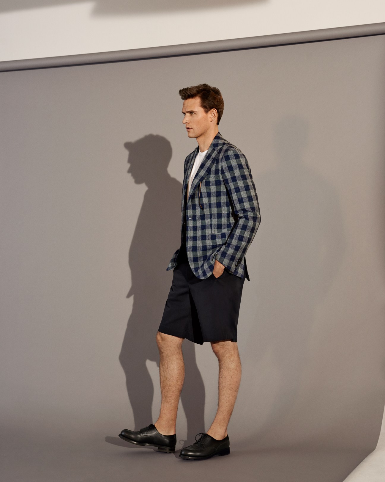 Man wearing checked blazer by Orazio Luciano, white t-shirt, dark shorts and black shoes.