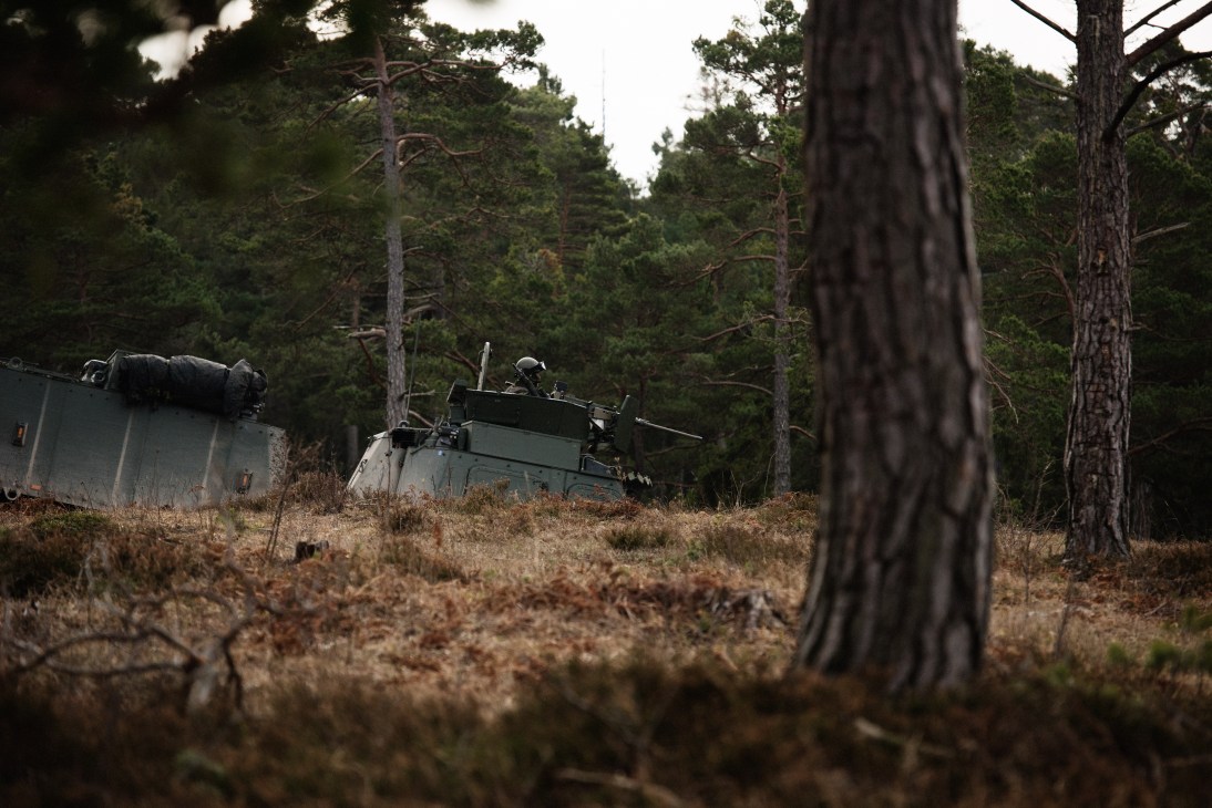 Swedish military tank positioned at Tofta firing range on Gotland with soldiers and forest backdrop.