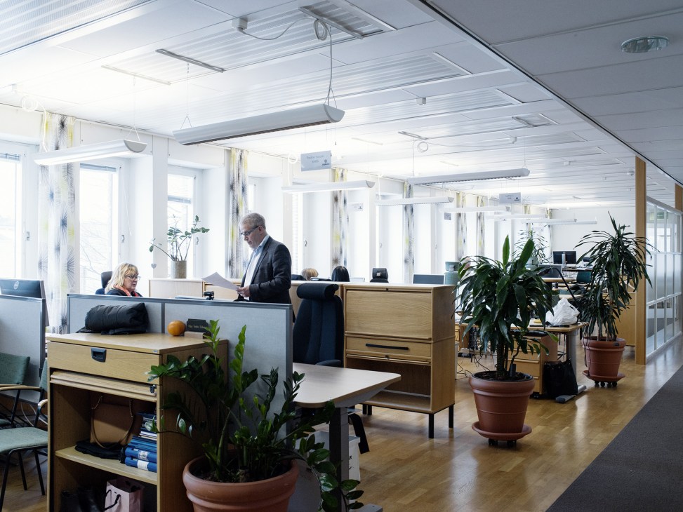 Modern office space with wooden desks, potted plants, and large windows in Scania's communications department.