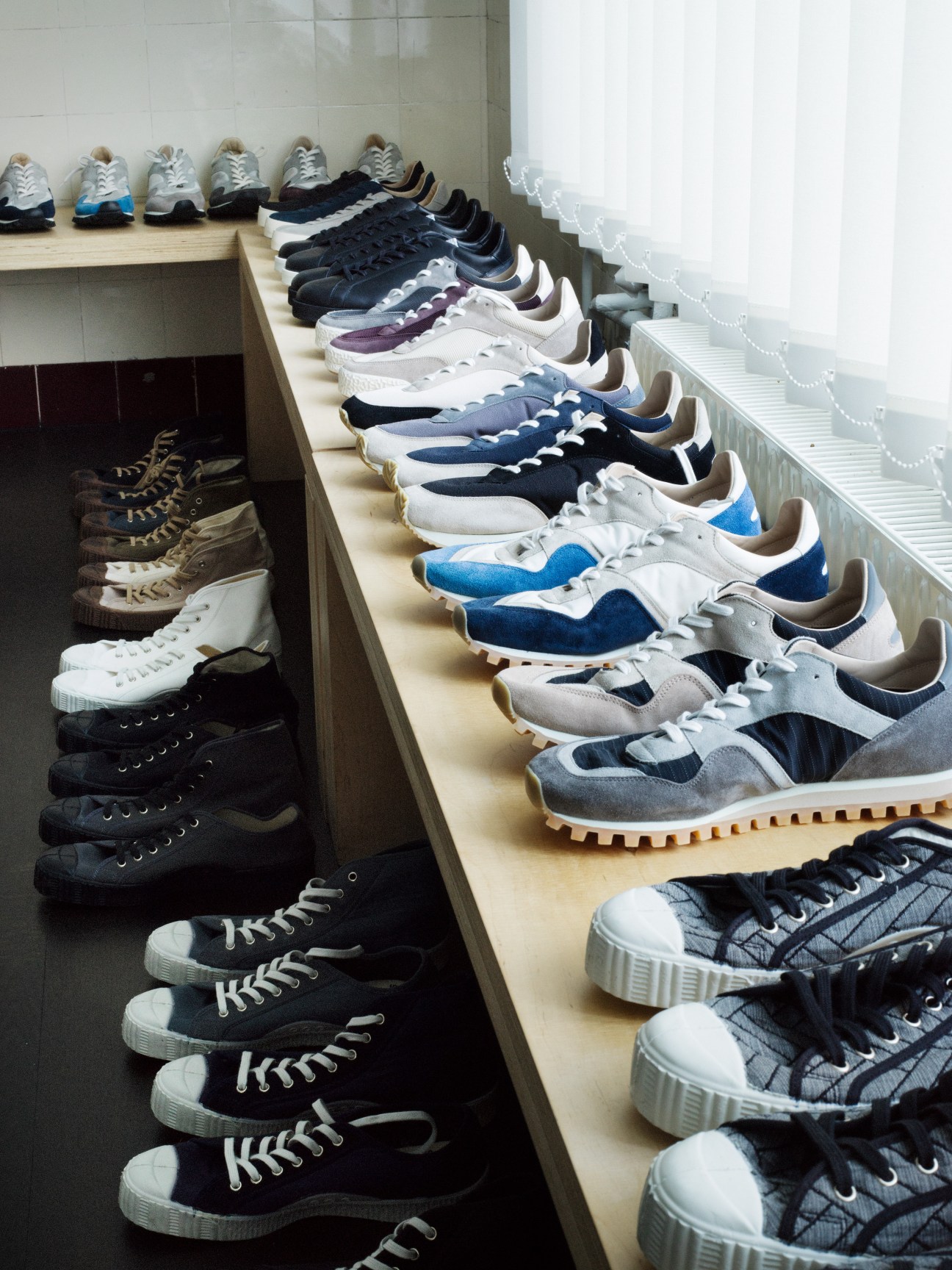 Collection of Spalwart retro-style sneakers in various colors displayed on wooden shelves.