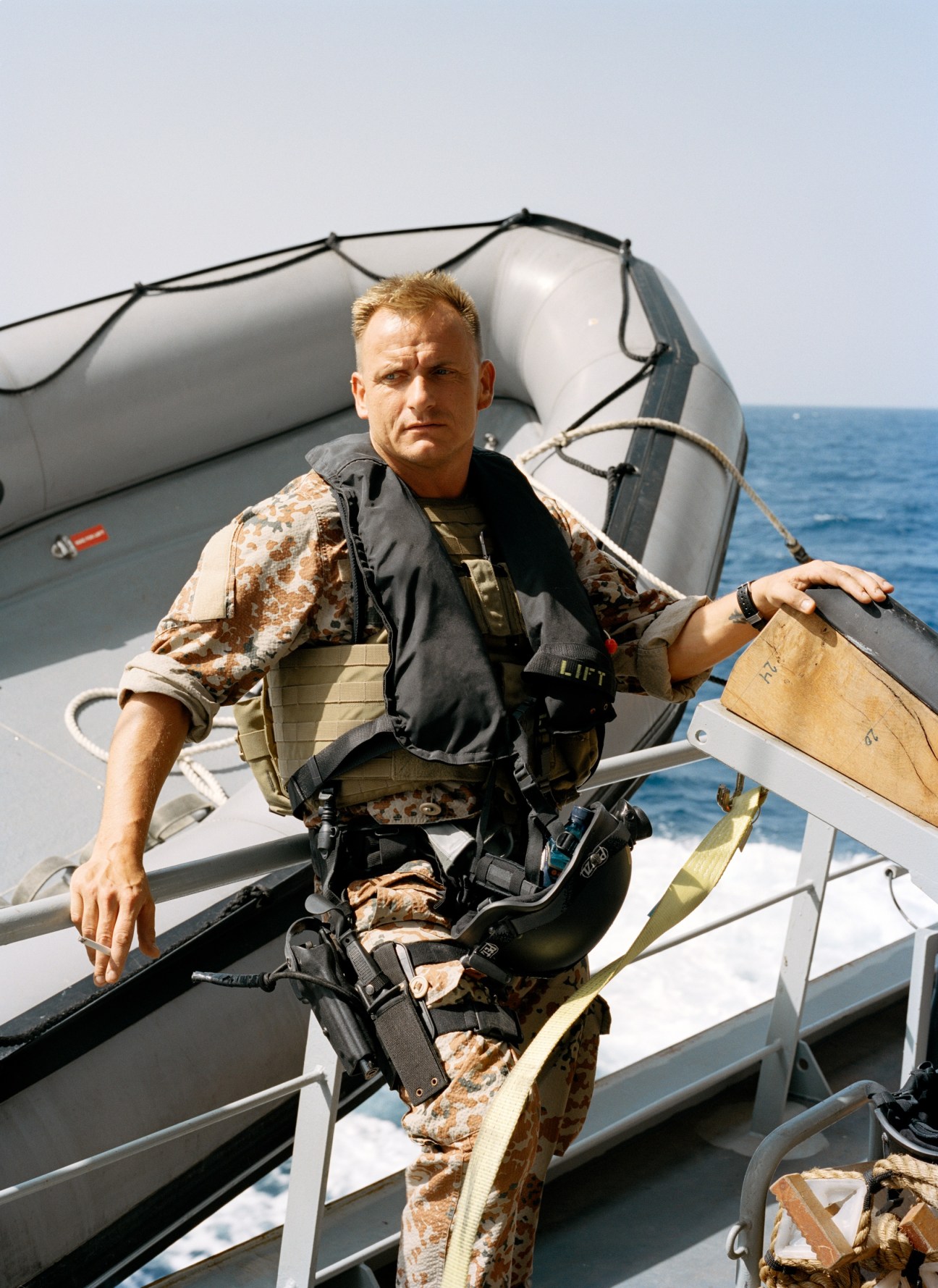 Danish Navy sailor in camouflage uniform and life vest stands in a rigid inflatable boat on the Indian Ocean.