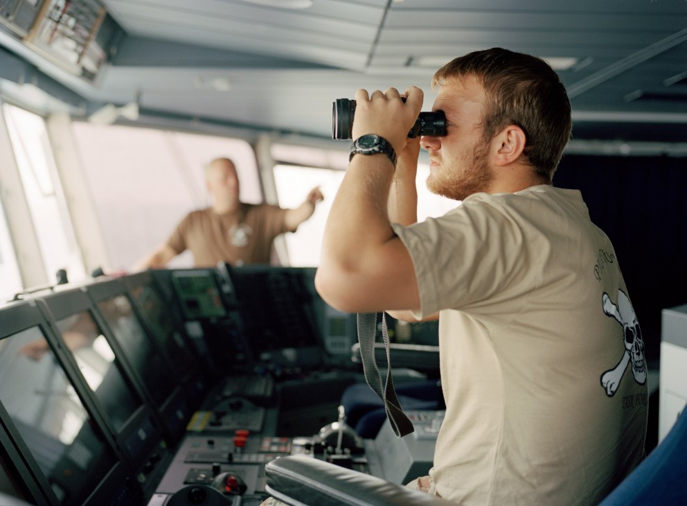 A Danish Navy petty officer uses binoculars to scan the horizon from the bridge of HDMS Absalon.