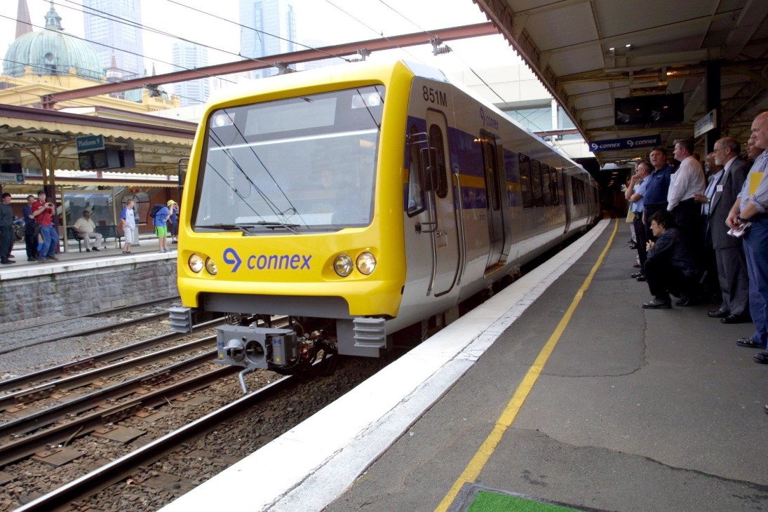 Yellow and purple Connex train at Melbourne station with passengers on platform.