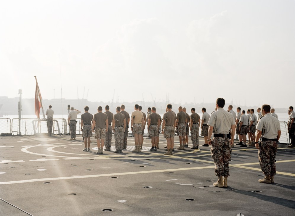 Danish Navy crew assembles on the helicopter deck of HDMS Absalon during morning muster in port.