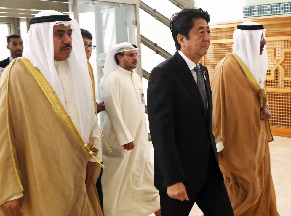 Prime Minister Shinzo Abe walking with Gulf Cooperation Council officials in traditional dress during diplomatic visit.