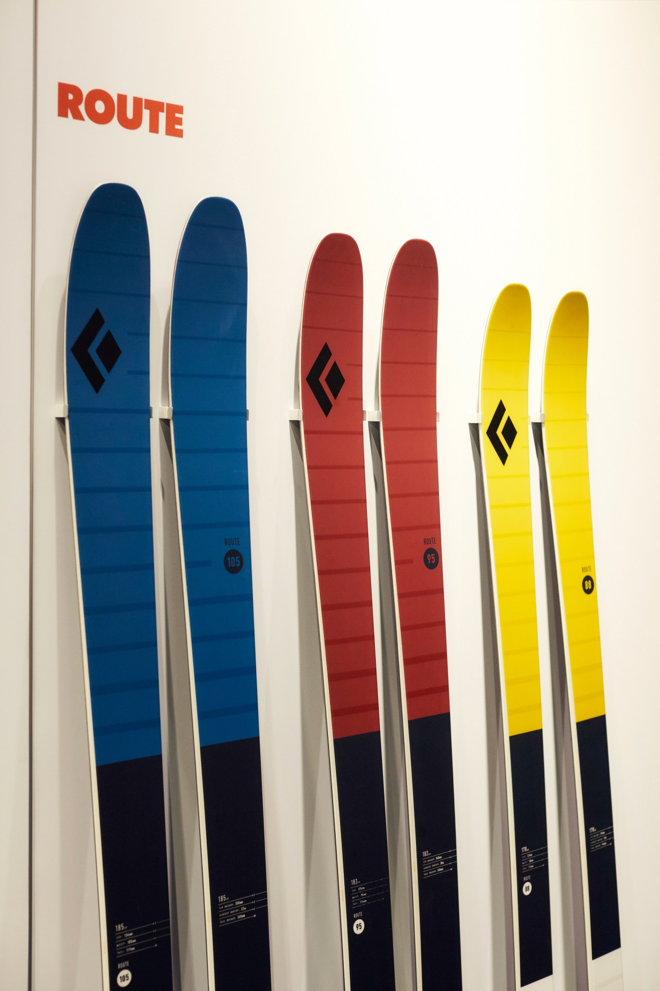 Black Diamond Route Skis displayed in blue, red, and yellow colorways with black diamond logos.