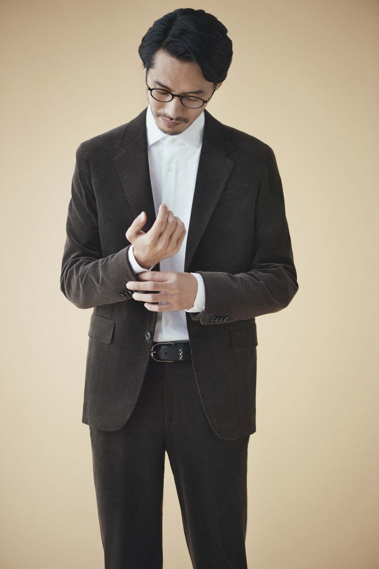 Man in charcoal blazer, white shirt, dark trousers and belt by Ermenegildo Zegna with Lindberg glasses