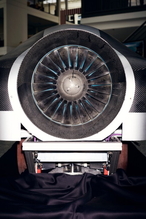 Close-up of a Hyperloop pod's circular electric motor with numbered fan blades and blue accents in a workshop setting.