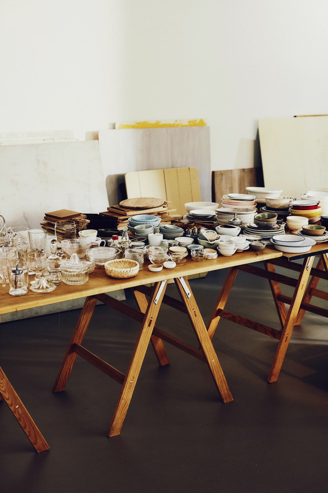 Wooden table laden with hundreds of dishes, plates, bowls, glasses and tableware props arranged for food photography.