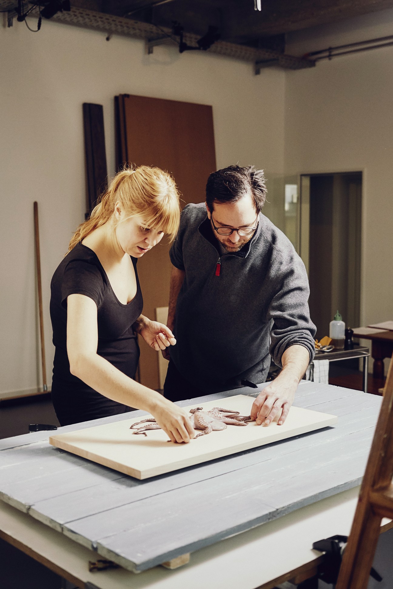Silke Schlund and Michael Wimmer arranging raw fish on a wooden board during a food photography shoot.