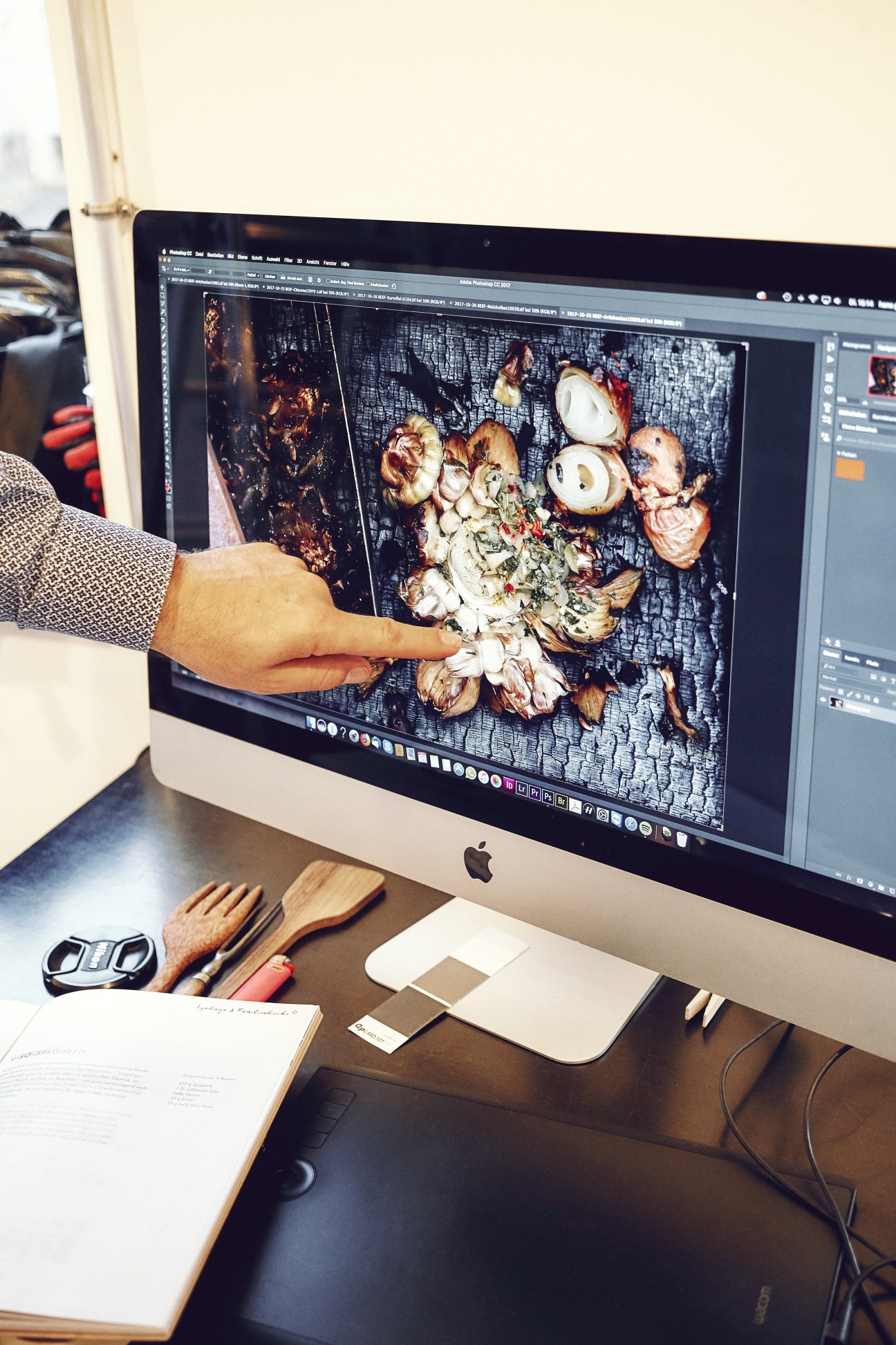 Food stylist pointing at cooked meat and vegetables displayed on a monitor during a photo shoot for Beef! magazine.
