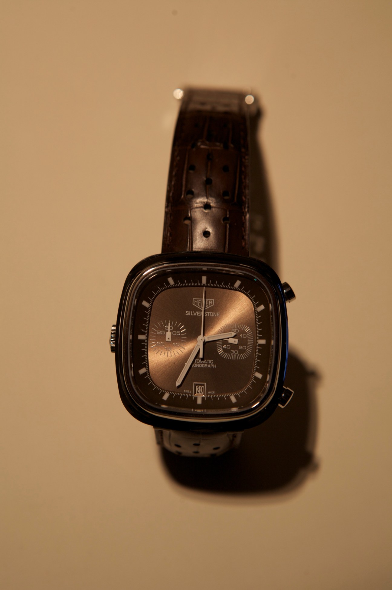 TAG Heuer's Silverstone re-edition chronograph watch with square case, brown leather strap, and bronze dial.