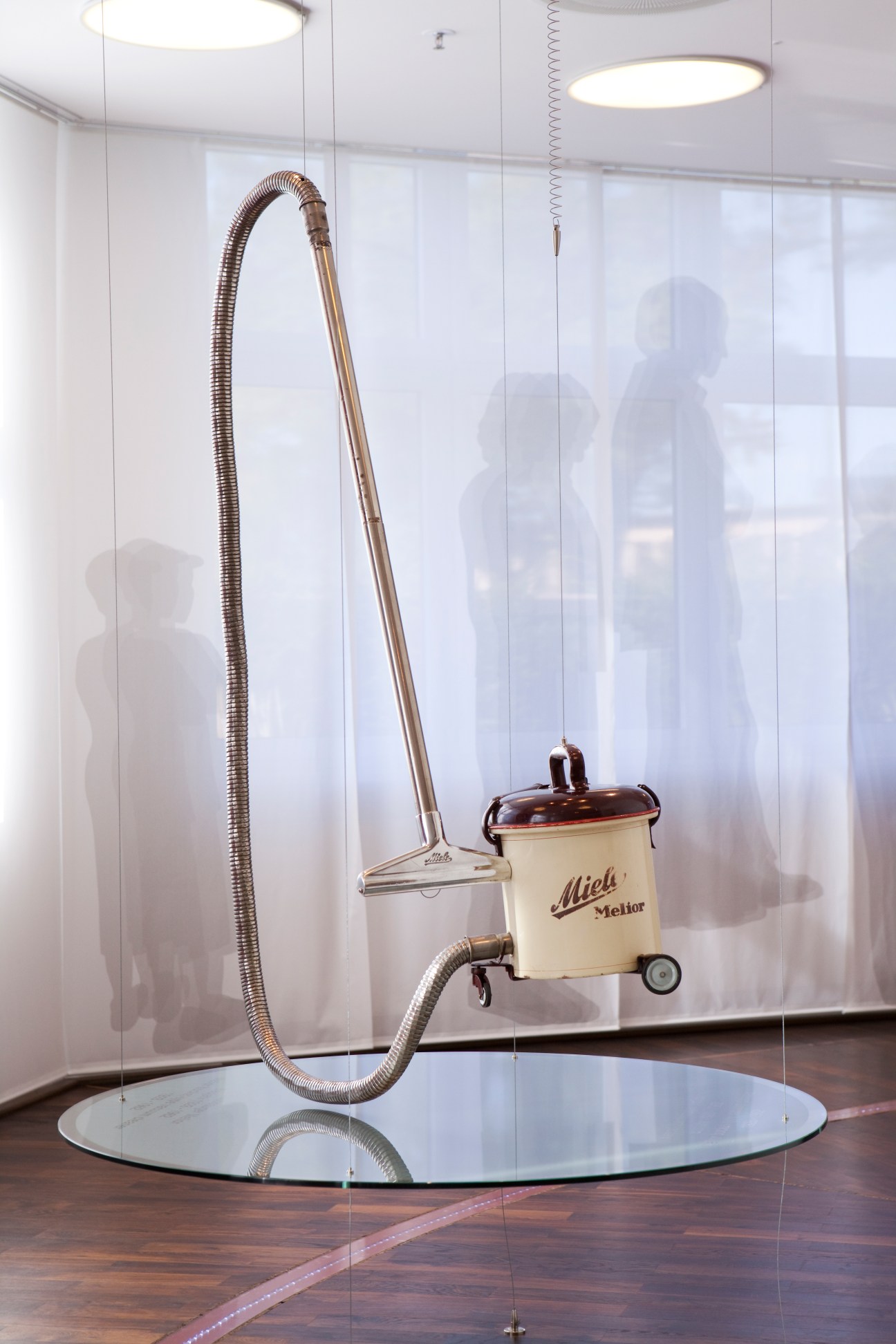 Vintage Miele Melior vacuum cleaner with cream-colored canister and flexible hose on display.