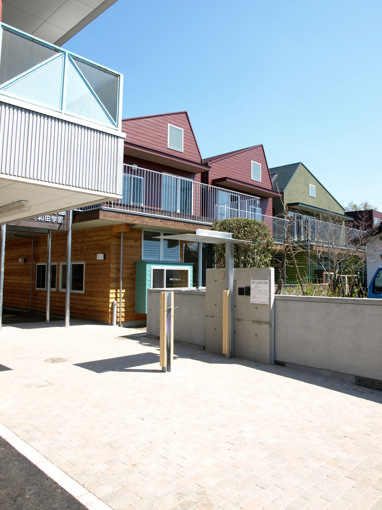 Exterior of Wada kindergarten building with wood cladding, metal railings and concrete play area.