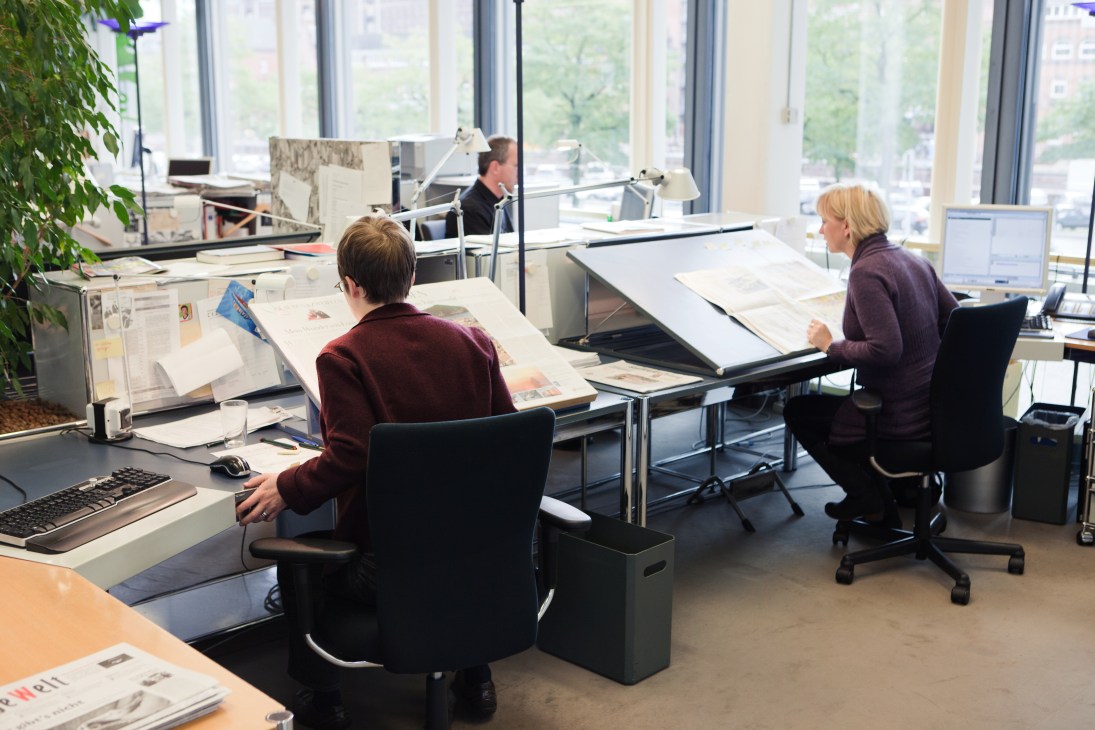 Der Spiegel fact-checking team members work at desks with documents and light tables in a modern office.