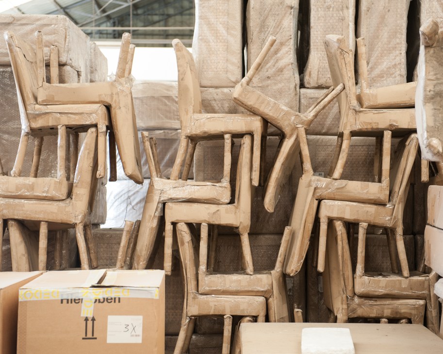 Wooden chairs wrapped in plastic stacked for shipping at Dedon factory.