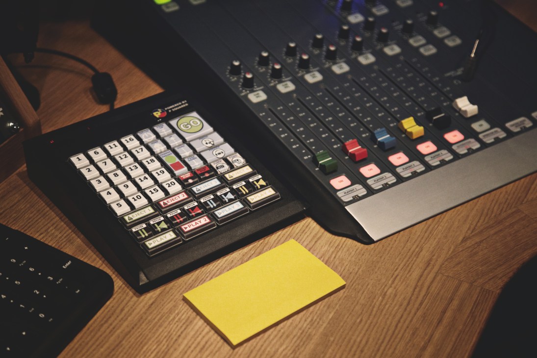 Audio mixing console and control panel on a wooden desk in Monocle 24's Studio Two