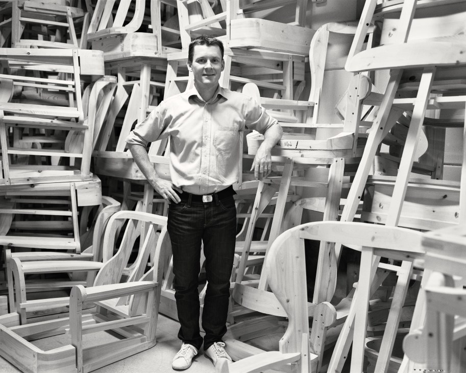 Håkan Sjögren stands surrounded by unfinished wooden chair frames in the Sjögren factory.