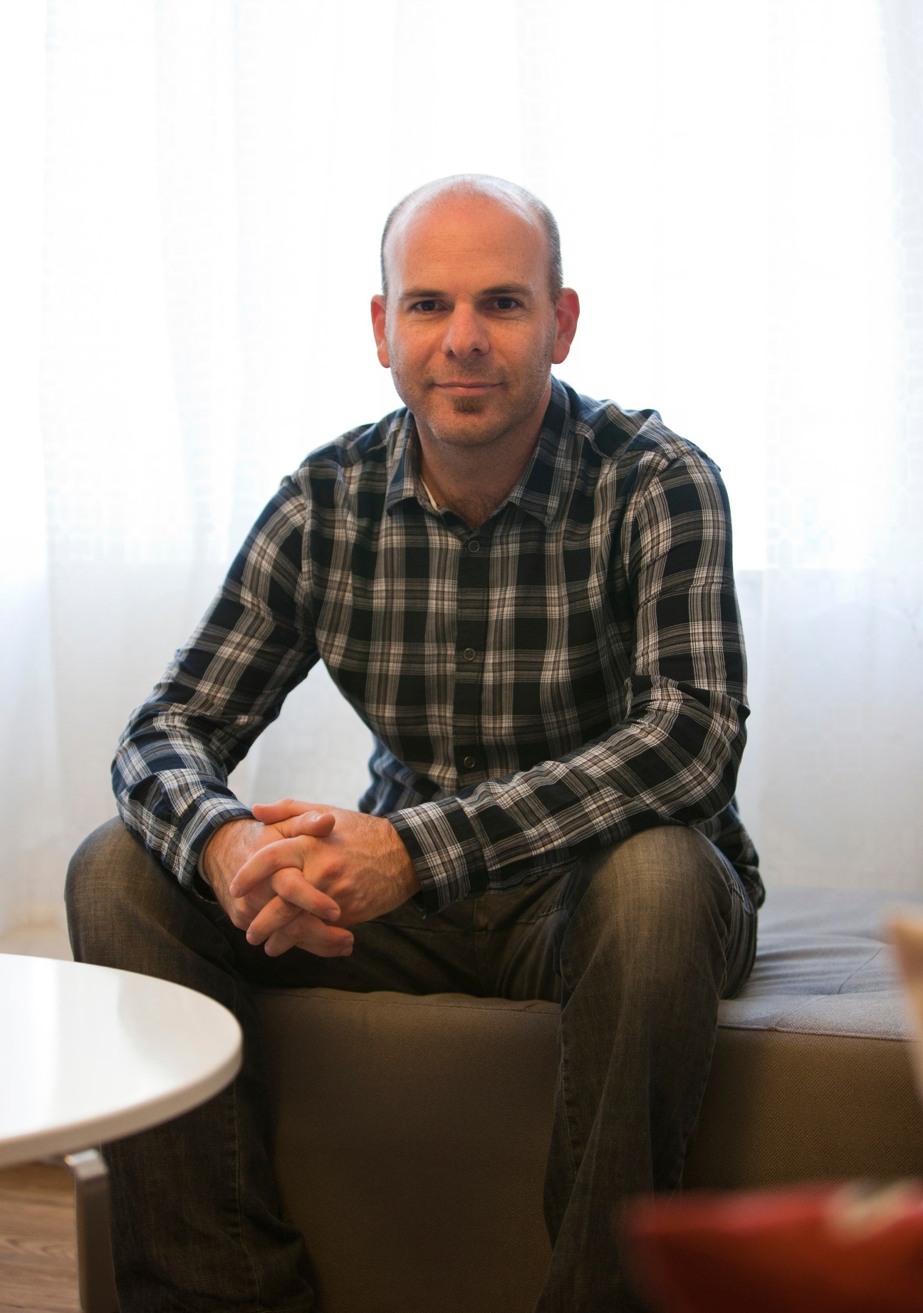 Paul Rozenberg, a 38-year-old financial director, sits in a portrait photo wearing a plaid shirt.