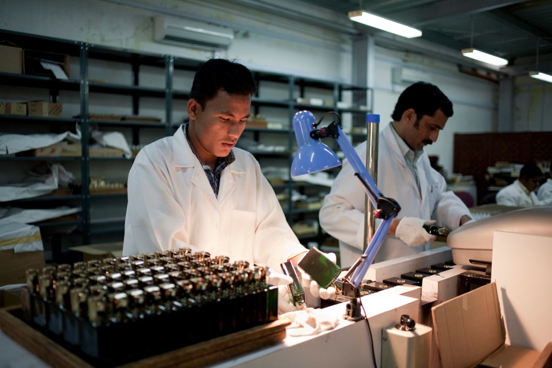 Workers in white lab coats inspecting perfume bottles at the Amouage bottling plant in Oman.