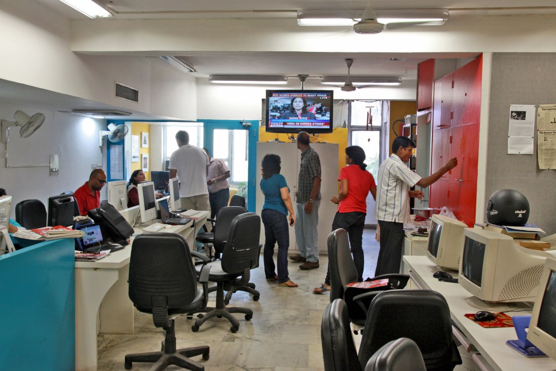 Tehelka magazine office staff gathered in a modern newsroom with colorful walls and computer workstations.