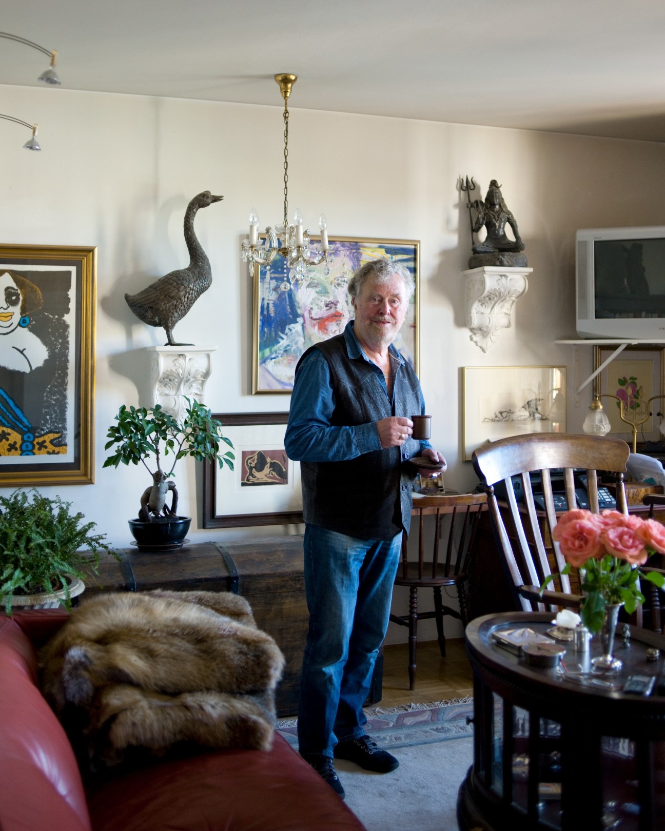 Actor Bukhard Gaffron standing in his apartment surrounded by art and sculptures.