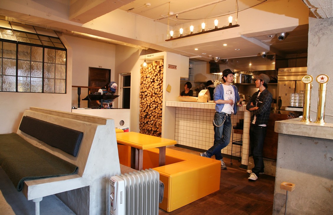 Interior of Number A diner in Tokyo with orange seating, white walls, and customers at the counter.