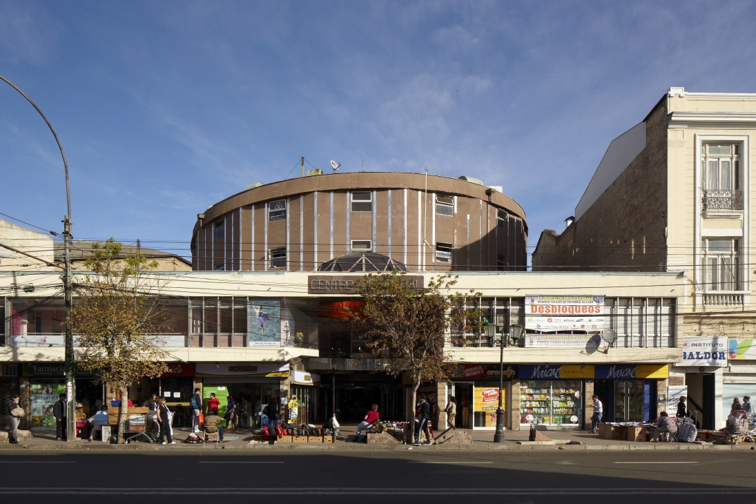 Street-level shops and businesses on Avenida Pedro Montt in Valparaíso with a distinctive curved mid-century building above.
