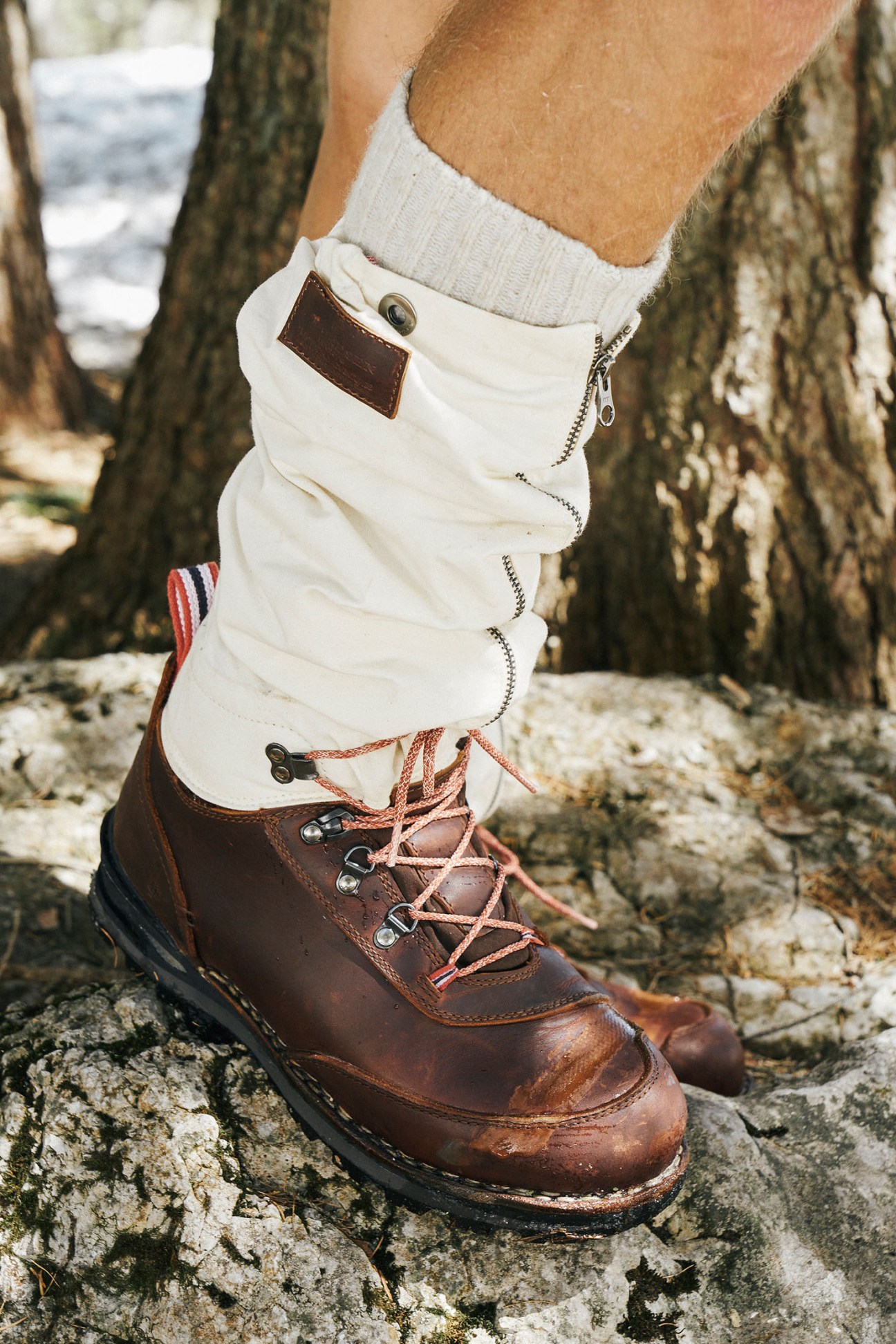 Brown leather hiking boot with white gaiters after mountain use, showing wear and dirt from outdoor testing