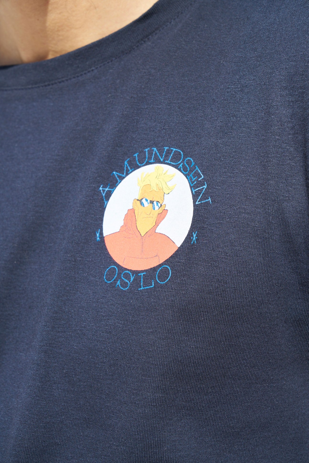 Navy t-shirt with Amundsen Sports logo featuring an illustrated portrait resembling Edmund Hillary in a circular design.