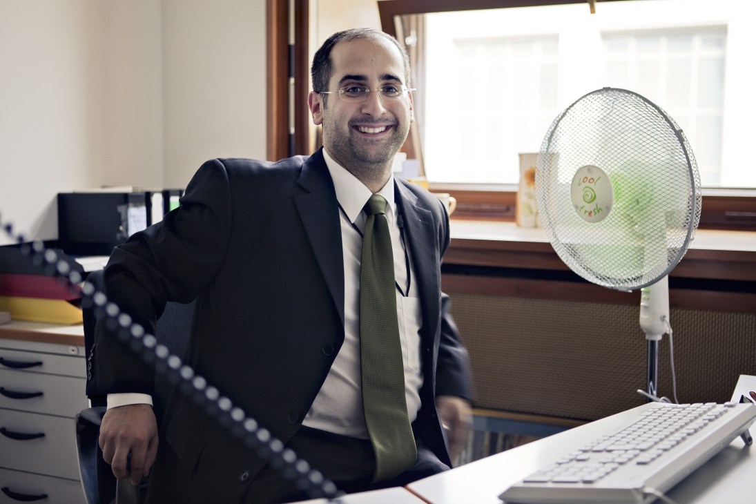 Aron Mir Haschemi, a desk officer at Germany's Federal Foreign Office, smiling in his office.