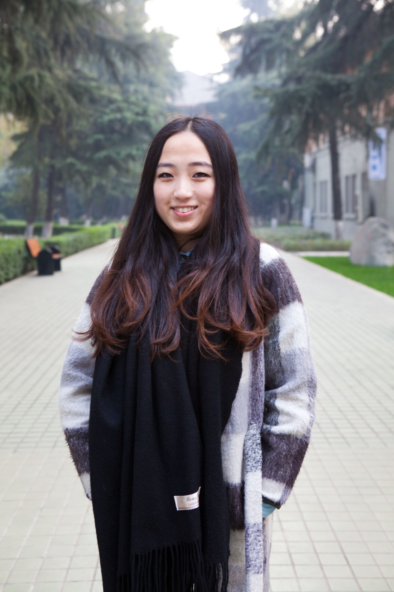 Railway engineering assistant Cici Song smiles at the camera on a tree-lined campus path.
