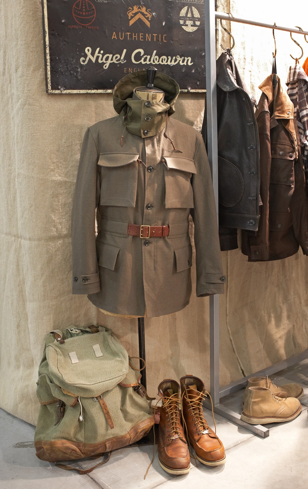 Nigel Cabourn display with khaki utility jacket, canvas backpack, and lace-up boots.