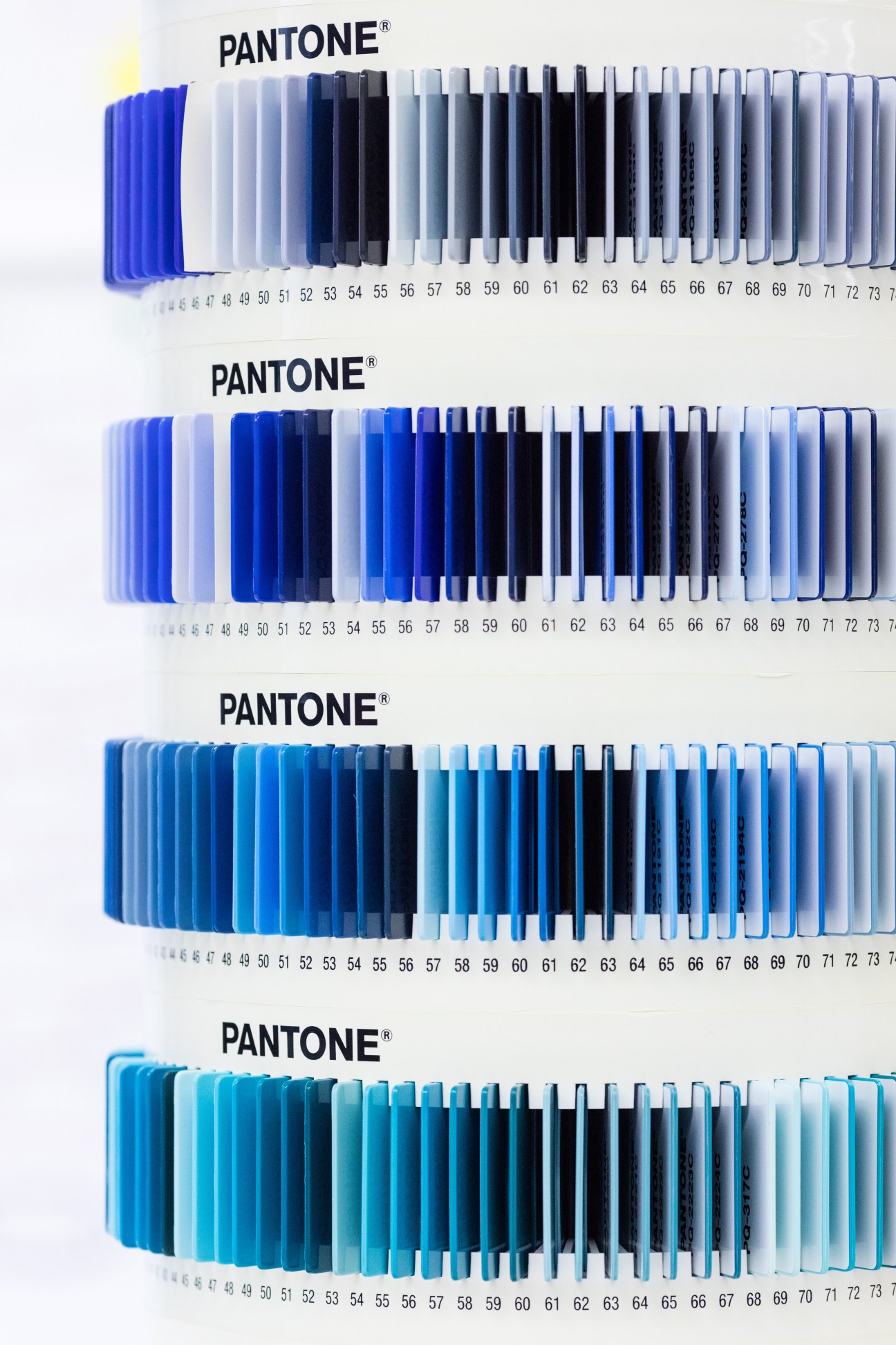 Four Pantone color fan decks displaying graduated shades of blue from bright to dark and light variations.