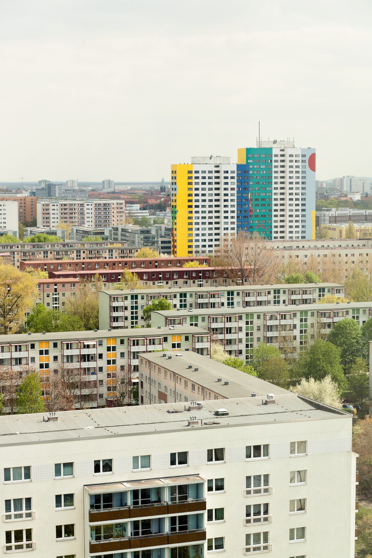Colorful prefabricated apartment buildings in Berlin's Lichtenberg district with high-rises in the background.