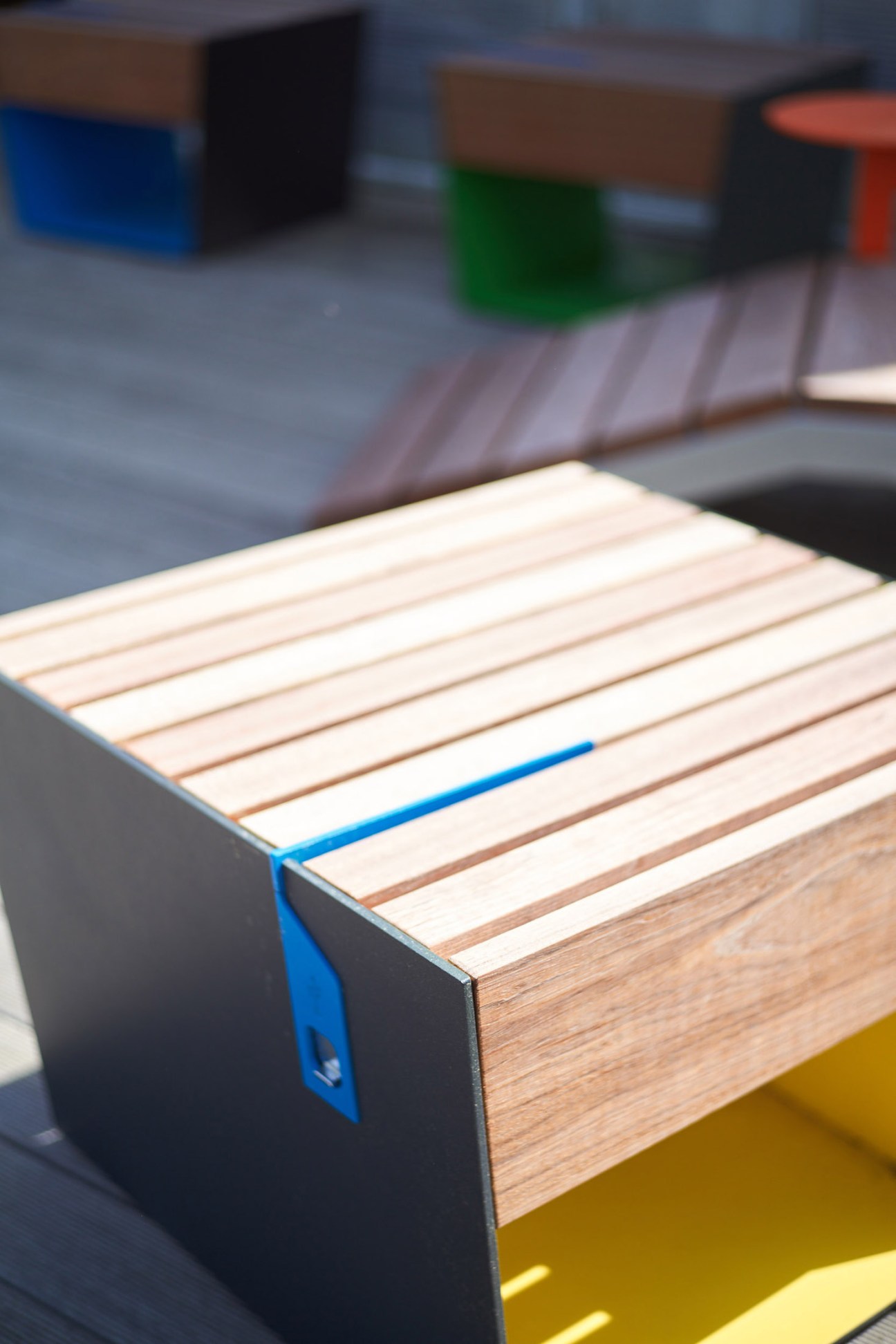 Mmcité's Smartcite street bench with wooden slats, blue side panel, and integrated USB charging point