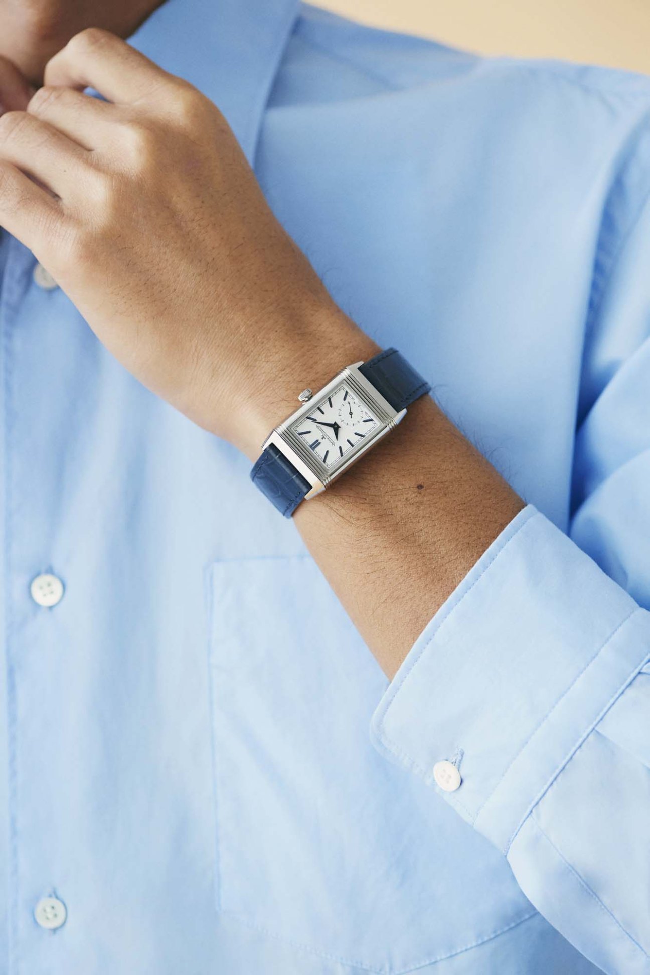 Man wearing light blue shirt and Jaeger-LeCoultre rectangular wristwatch with navy leather strap