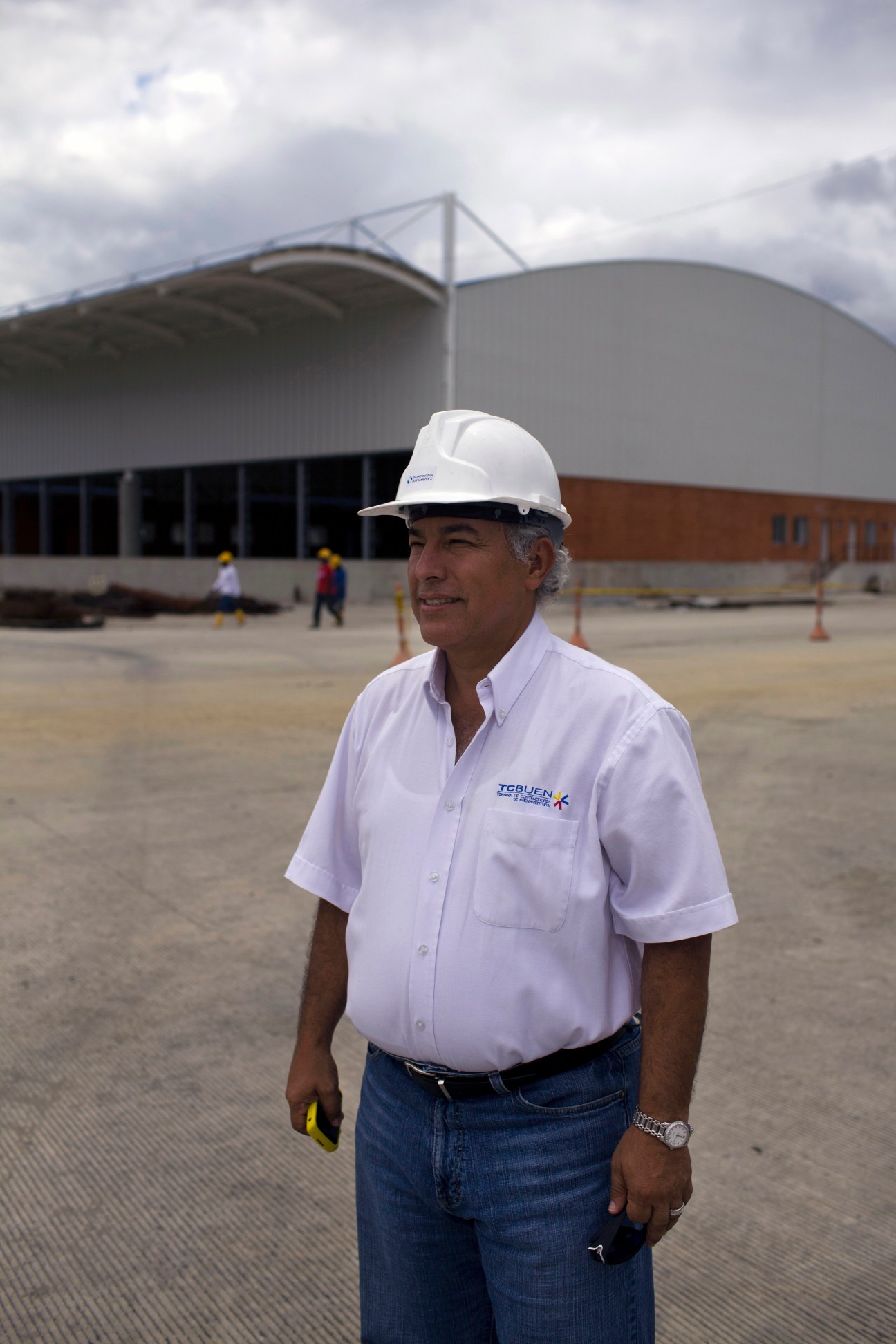 Entrepreneur Oscar Isaza wearing a hard hat and white shirt at a construction site for new port facilities in Buenaventura.