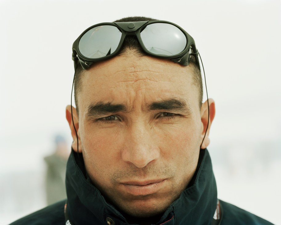 Close-up portrait of a Moroccan military athlete wearing ski goggles on his forehead and dark winter gear.
