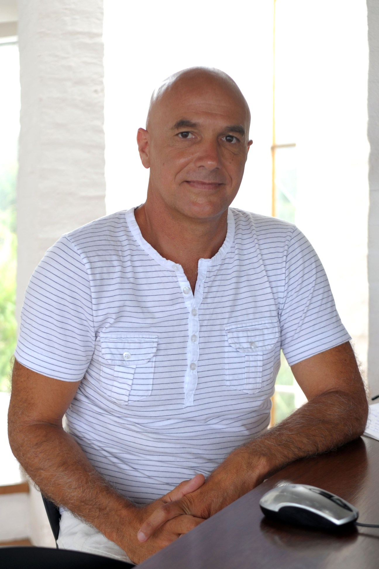Portrait of Matías Sambarino, an architect, sitting at a desk wearing a blue striped shirt.