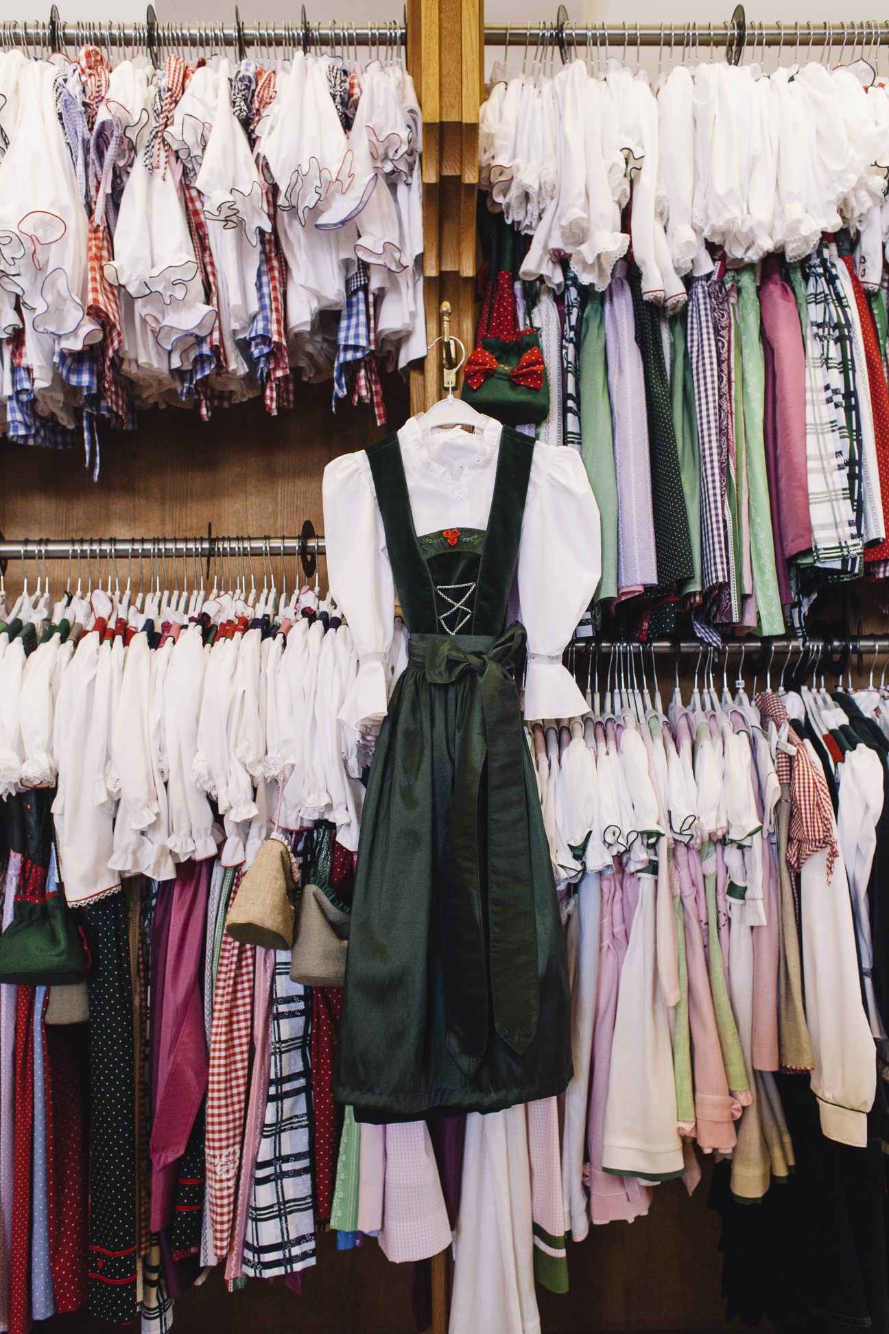 Traditional Austrian clothing display at Loden Plankl with white blouses and colorful dirndl skirts on hangers.