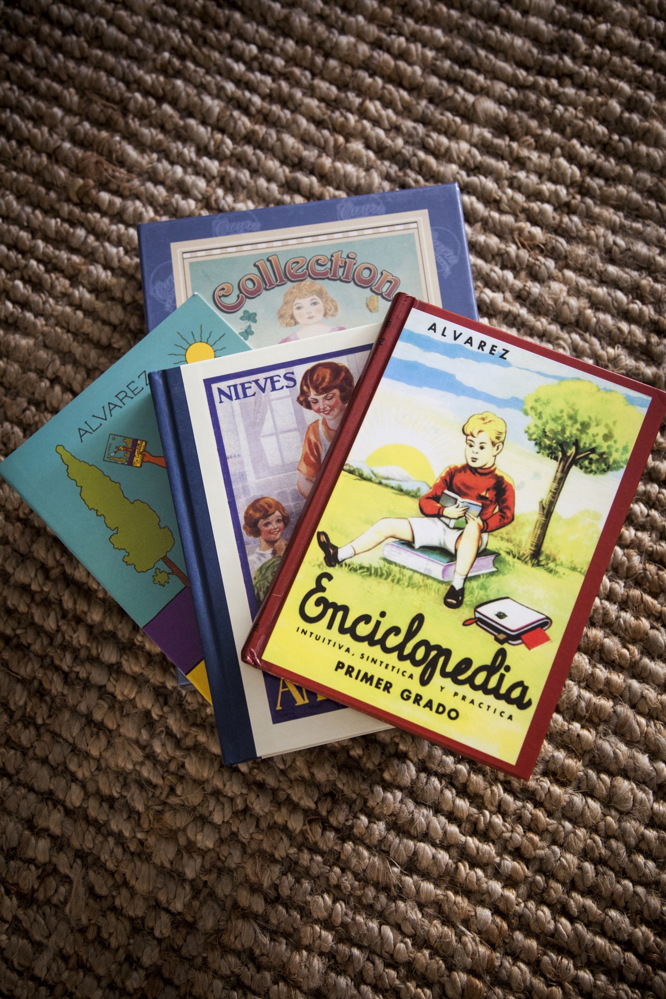 Three vintage Spanish textbooks displayed on a woven beige surface.