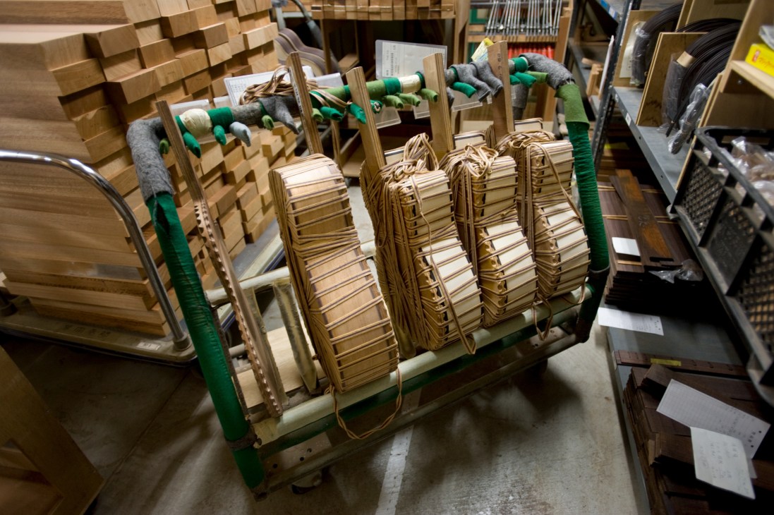 Yamaha acoustic guitar bodies in various stages of construction on a wooden rack in the factory workshop.